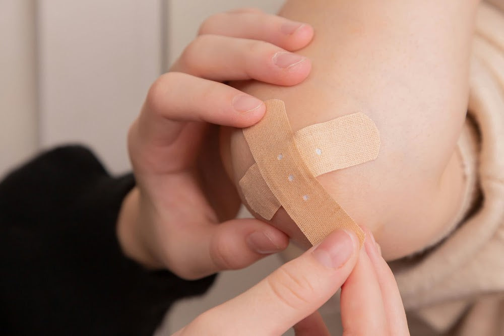 A scratched elbow with a bandage applied during the closing process