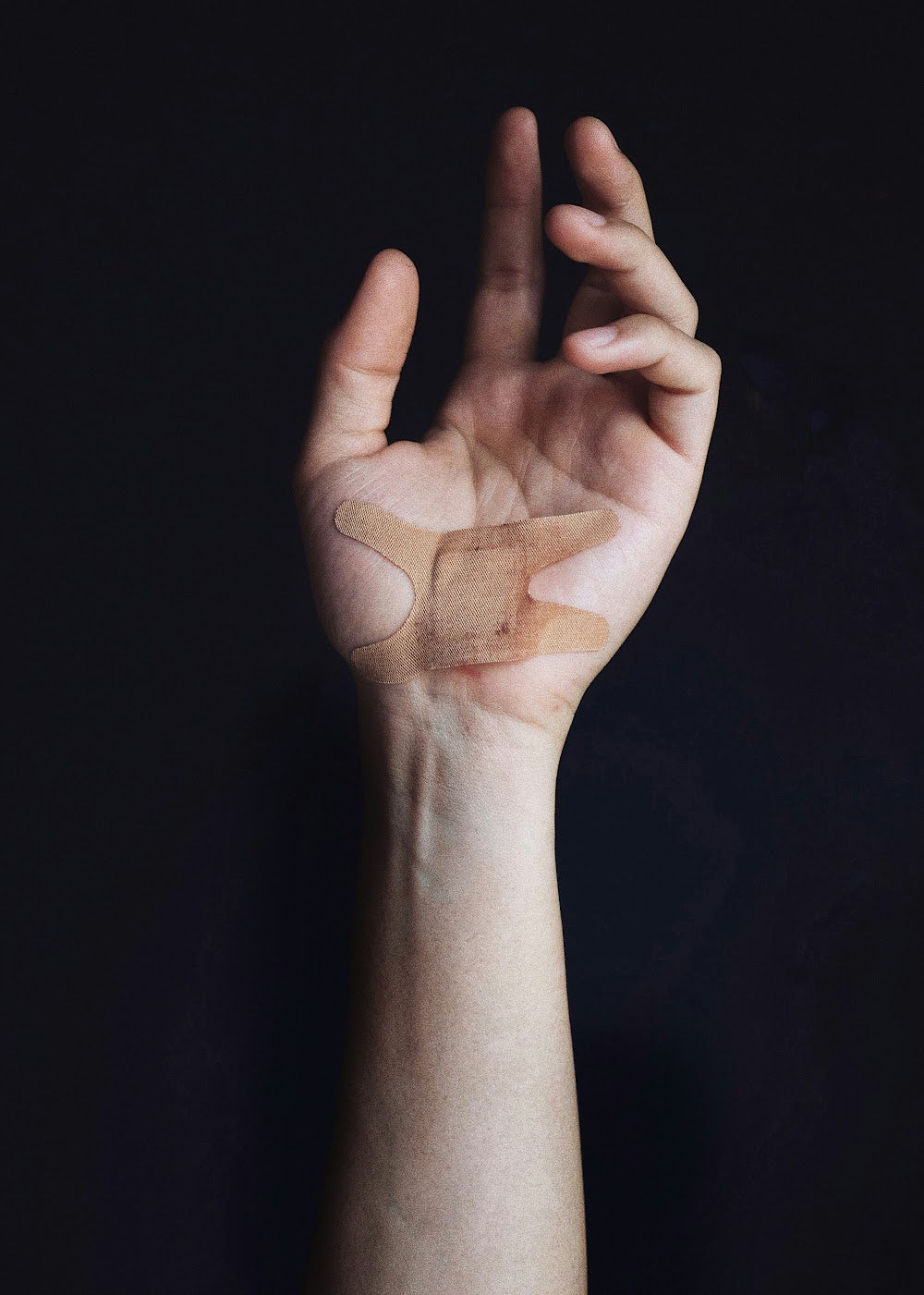 A scratched hand with a bandage applied, relevant to showering with a minor wound