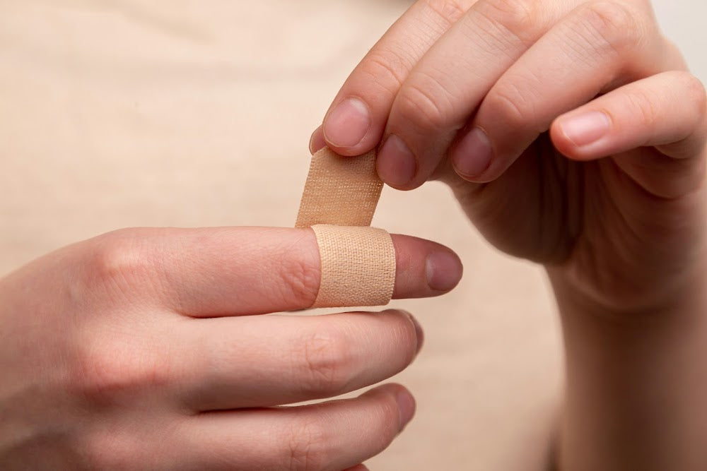 A bandaid being applied and wrapped on a finger
