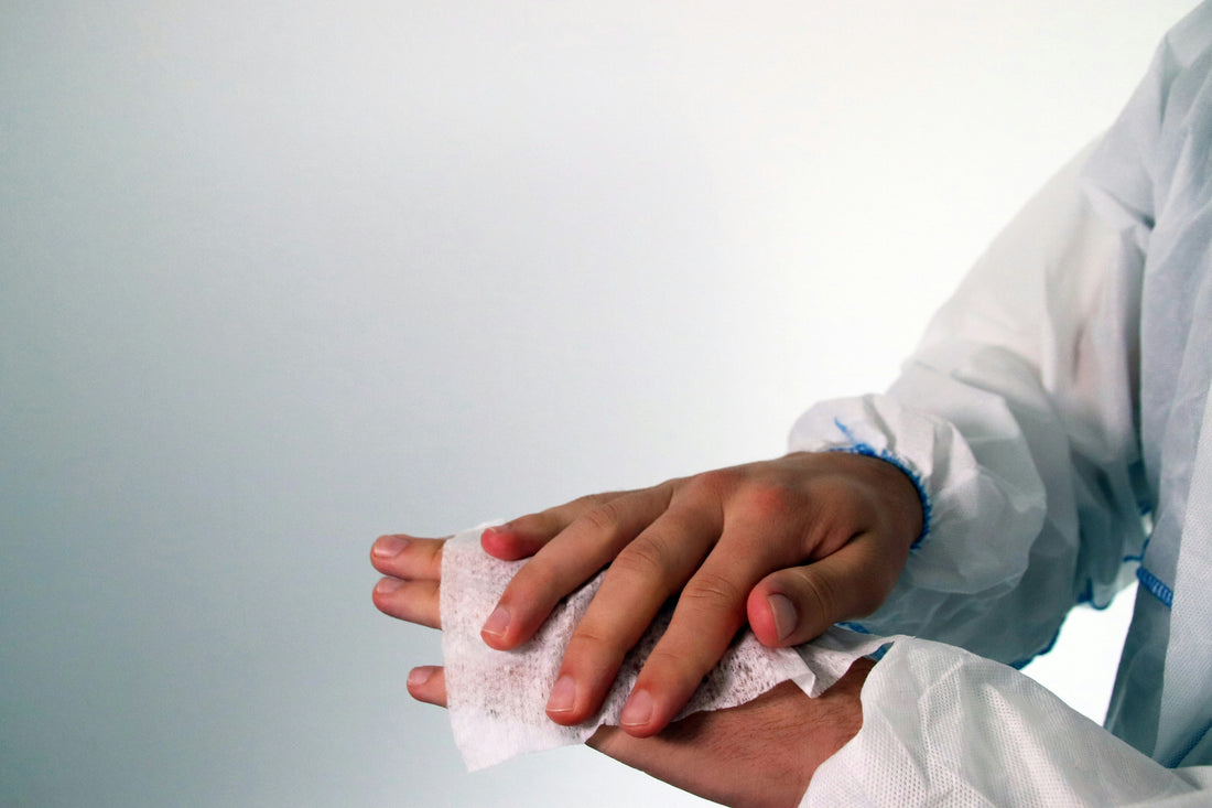 A person preventing infection by cleaning their hand with an antiseptic wipe